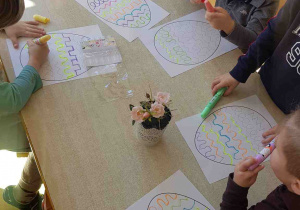 Dzieci wykonują ćwiczenia grafomotoryczne, ozdabiając na kartce duże pisanki