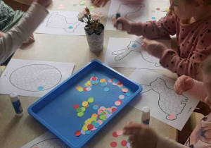 Dzieci wyklejają kolorowymi kołami świąteczne szablony
