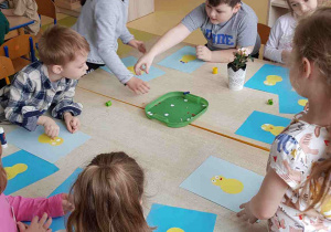 Dzieci przyklejają na błękitne tło żółtego kurczaczka