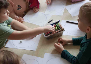 Dzieci losują kostką wzór, który naniosą na pisankę