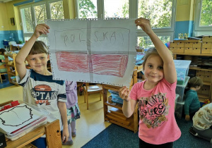 Chłopiec i dziewczynka prezentują wykonaną przez siebie flagę Polski