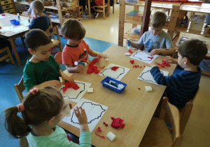 Dzieci przy stoliku wykonują prace plastyczne