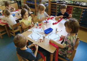 Dzieci ozdabiają mapę Polski bibułą