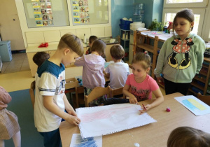 Chłopiec i dziewczynka rysują kredkami flagę Polski