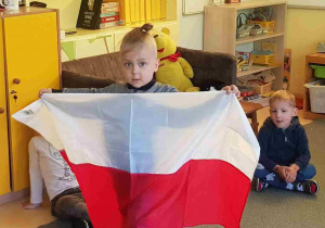 Chłopiec trzyma w rękach flagę Polski