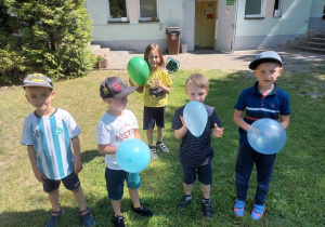 Chłopcy pozują do zdjęcia z nadmuchanymi przez siebie balonami