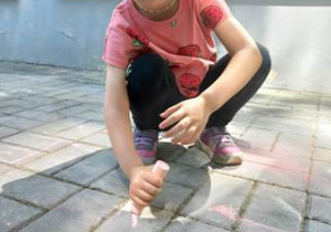 Dziewczynka maluje kredą na tarasie przedszkolnym