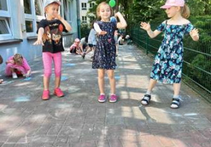 Trzy dziewczynki tańczą układ taneczny na przedszkolnym tarasie