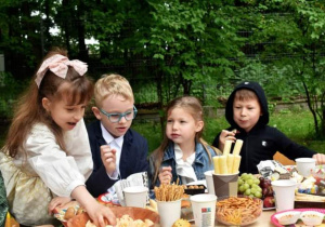 dzieci siedzą przy stoliku podczas pikniku