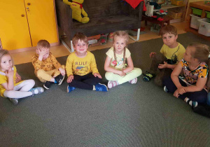 Dzieci siedzą w kręgu ubrane w kolorze grupy