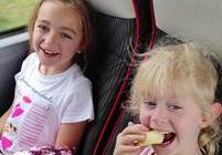 Dwie dziewczynki siedzą w autokarze i jedzą przekąski