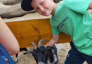 Chłopiec pozuje do pamiątkowego zdjęcia z kozą