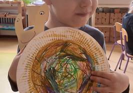 Kacperek prezentuje wykonaną przez siebie prace plastyczną "Ślimak" wykonaną z papierowego talerzyka pomalowanego pastelami
