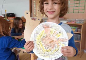 Chłopiec prezentuje swojego ślimaka wykonanego z papierowego talerzyka oraz elementów kolorowego papieru