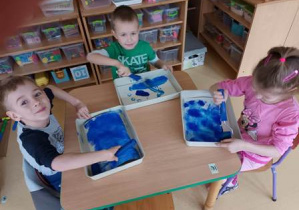 Dzieci malują granatową farbą tło do pracy plastycznej