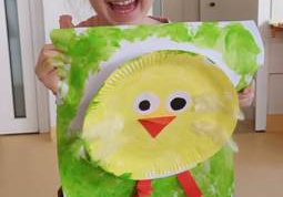 Anielka z zadowoleniem prezentuje wykonaną przez siebie pracę plastyczną "Wielkanocny kurczaczek"