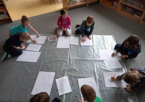 Dzieci starsze na dywanie rysują zajączka według wylosowanego w grze matematycznej kodu