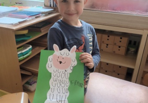 Chłopiec prezentuje wykonaną przez siebie pracę plastyczną przedstawiającą lamę
