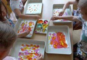 Grupa dzieci barwi farbami przy użyciu pipet chusteczki higieniczne