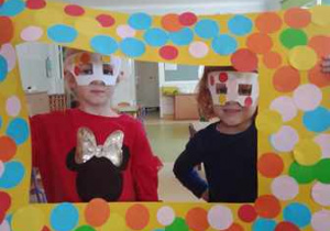 Dwie dziewczynki pozują do zdjęcia w okularach oraz z ramką ozdobioną tematycznie w kolorowe kropki