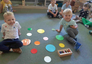 Chłopcy układają kolorowe kropki na dywanie