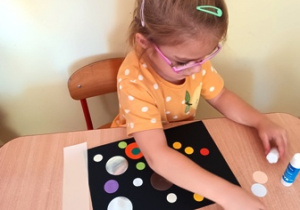 Julia przykleja kolorowe kropki na czarnym tle