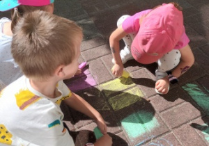 Dzieci malują kolorowymi kredami na tarasie przedszkolnym