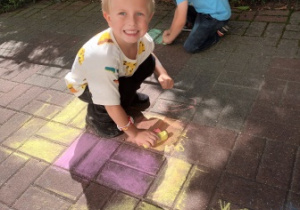 Natan maluje kredą taras przedszkolny