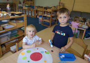 Chłopiec i dziewczynka wykonują pracę plastyczną siedząc przy stoliku