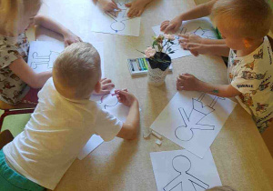 Dzieci kolorują obrazki przy stole