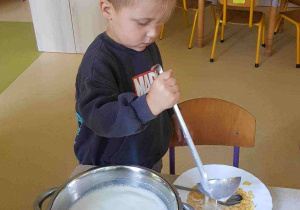Chłopiec nalewa mleko do talerza