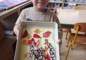 Chłopiec prezentuje ukończoną przez siebie pracę plastyczną pt. "Drzewo"