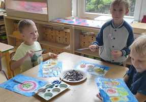 Chłopcy w czasie zabawy plastycznej "Jesienne Drzewa" malują tło farbami