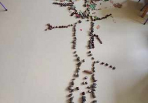 Zdjęcie przedstawia sylwetę drzewa ułożoną przez dzieci z materiału przyrodniczego - liści, gałęzi, kasztanów oraz szyszek