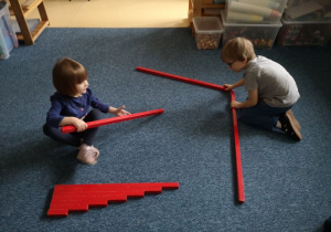 Chłopiec i dziewczynka układają meandrom z czerwonych sztang