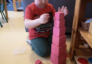 Chłopiec układa różową wieżę