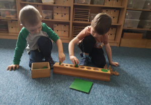 Dwóch chłopców układa zielone cylindry