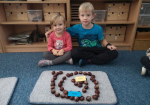 Chłopiec i dziewczynka prezentują wykonaną przez siebie pracę - ślimaka z kasztanów