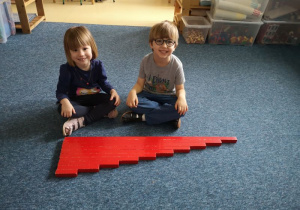 Chłopiec i dziewczynka prezentują wykonaną przez siebie pracę - czerwone sztangi