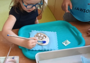 Dziewczynka maluje niebieską farbą na powierzchni masy solnej