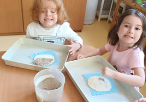 Dziewczynka i chłopiec w czasie wykonywania pracy plastycznej posypują paskiem masę solną