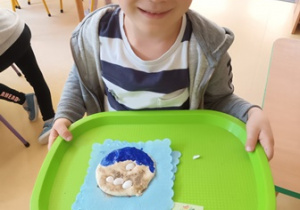 Chłopiec prezentuje wykonany przez siebie z masy solnej "Nadmorski obrazek"