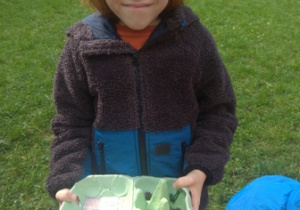 Chłopiec prezentuje odnaleziony w ogrodzie materiał przyrodniczy