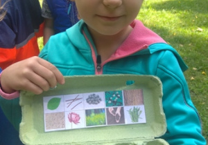 Dziewczynka prezentuje odnaleziony w ogrodzie materiał przyrodniczy