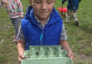 Chłopiec prezentuje odnaleziony w ogrodzie materiał przyrodniczy