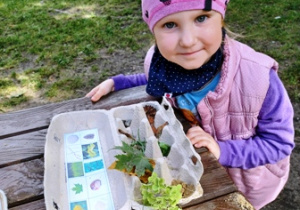 Dziewczynka pokazuje odnaleziony materiał przyrodniczy ułożony w pudełku