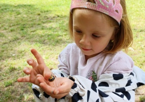 Dziewczynka trzyma w ręku ślimaka znalezionego w ogrodzie