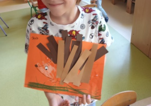 Chłopiec pozuje do zdjęcia ze zrobioną przez siebie pracą plastyczną przedstawiająca jeża