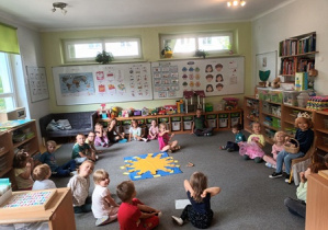 Zdjęcie przestawia grupę dzieci siedzących w kręgu podczas urodzin Tadzia, w środku kręgu leży pomoc edukacyjna "Urodzinowe Słoneczko"