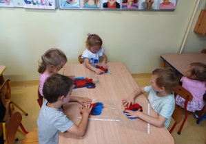 Dzieci w czasie wykonywania eksperymentu - łączenia koloru niebieskiego i czerwonego